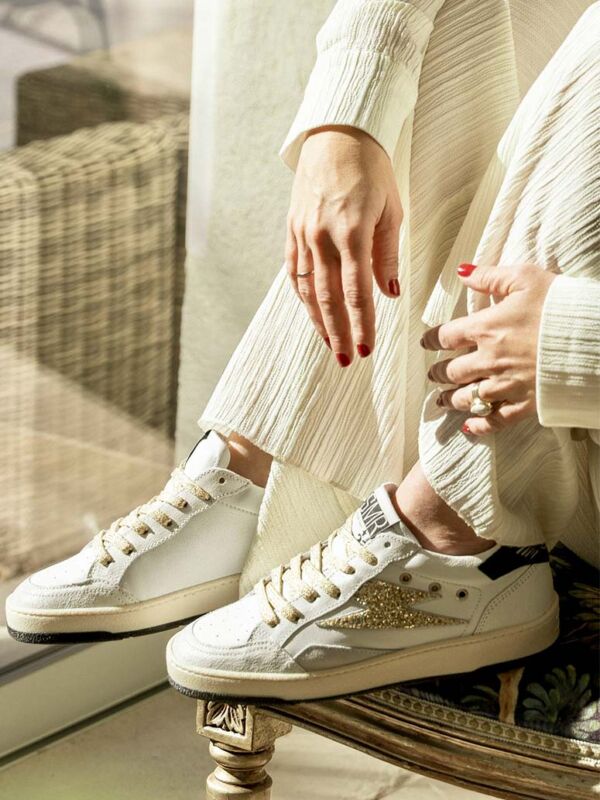 Sneakers femme SMR23 Dany blanches avec éclair doré pailleté, lacets beige doré et semelle écrue, portées en intérieur