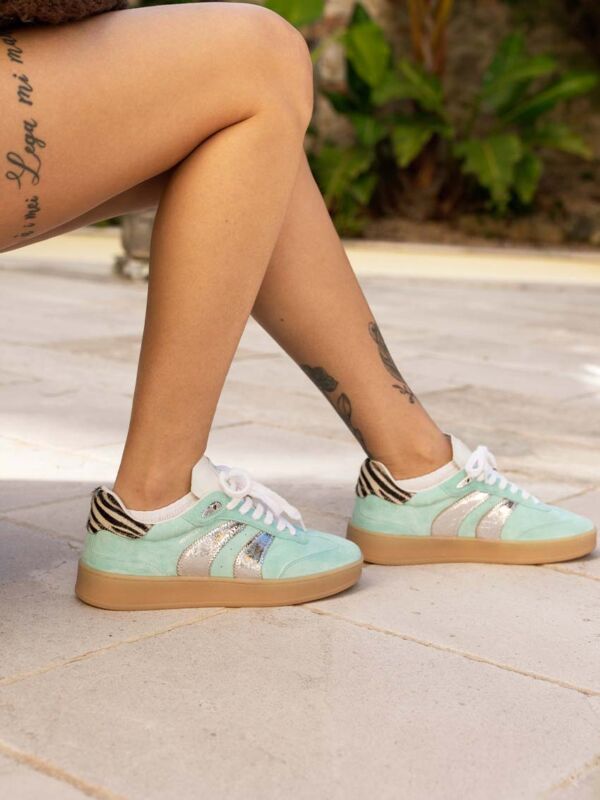 Paire de baskets femme Crime London Wembley Mint portée en position assise, avec semelle gomme, bandes argentées et détail zèbre au talon.