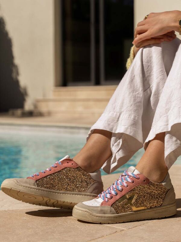 Sneakers Serafini San Diego glitter gold : baskets dorées pailletées avec lacets tricolores rouge blanc bleu, portées au bord de la piscine avec un pantalon lin blanc. Style luxe décontracté.