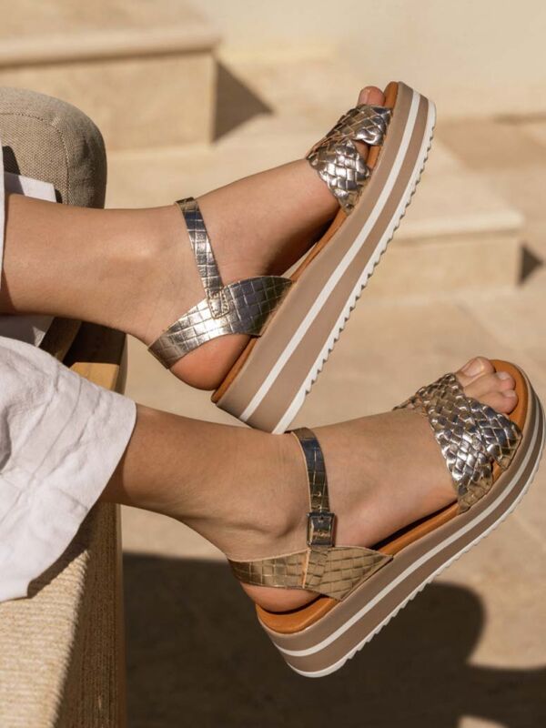 Sandales femme confortables et élégantes de la marque Oh My Sandals, modèle compensé à brides métalliques tressées, porté avec un pantalon blanc en lin dans un cadre estival.