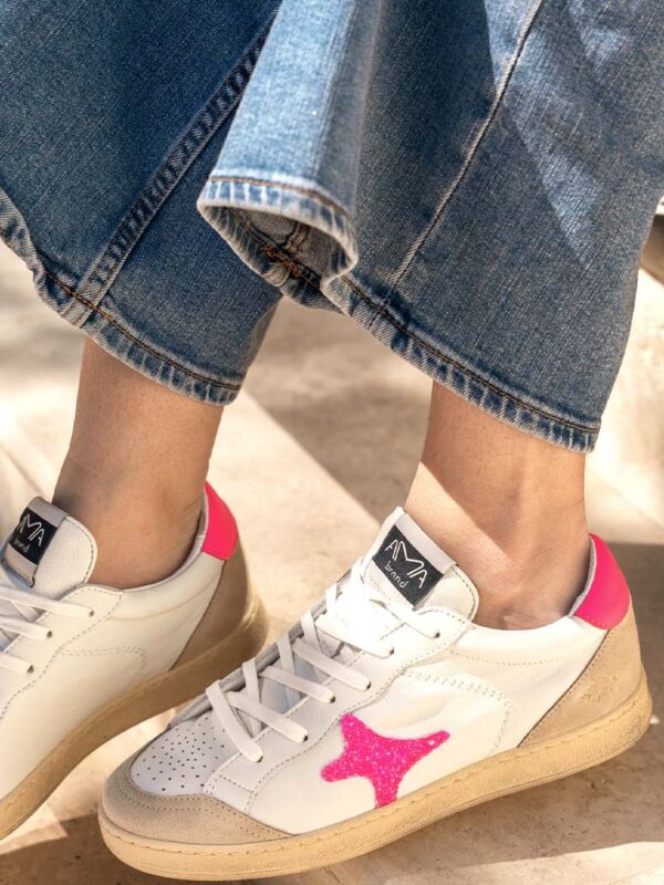 Sneakers femme Ama Brand Deluxe en cuir blanc et suède beige, ornées d'une étoile rose pailletée sur le côté et d'une semelle gomme, portées avec un jean bleu délavé.