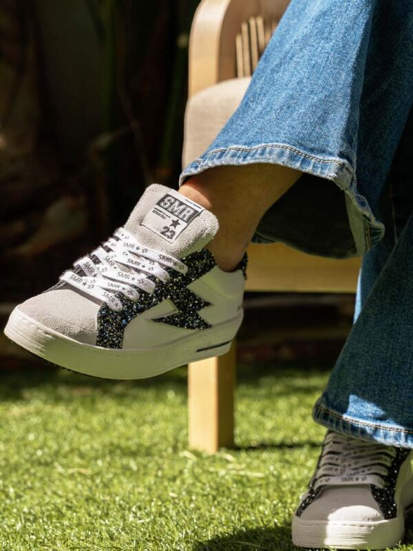 Sneakers SMR23 Maya C780 blanc et gris : logo éclair pailleté noir, lacets imprimés SMR 23, suède gris sur le bout et semelle plateforme blanche.
