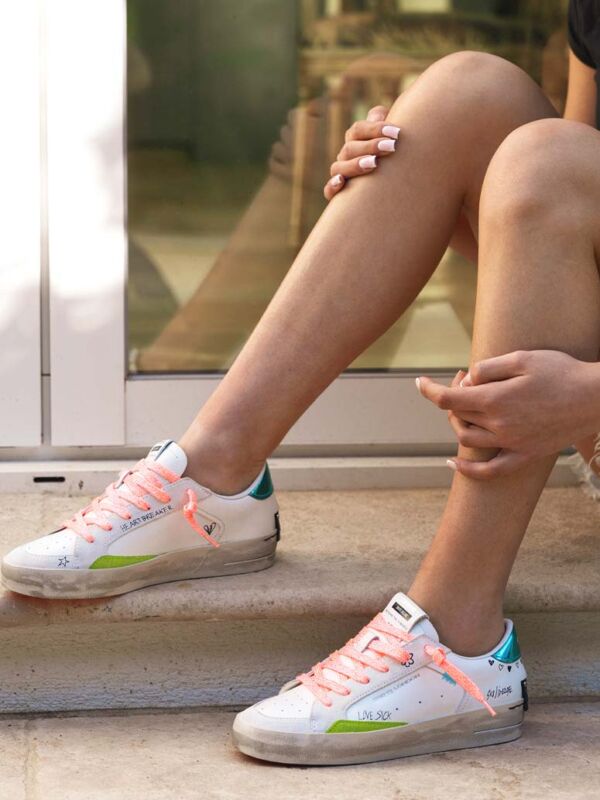 Sneakers femme Crime London blanches avec lacets corail, détails vert fluo et turquoise, inscriptions graphiques et semelle effet vintage