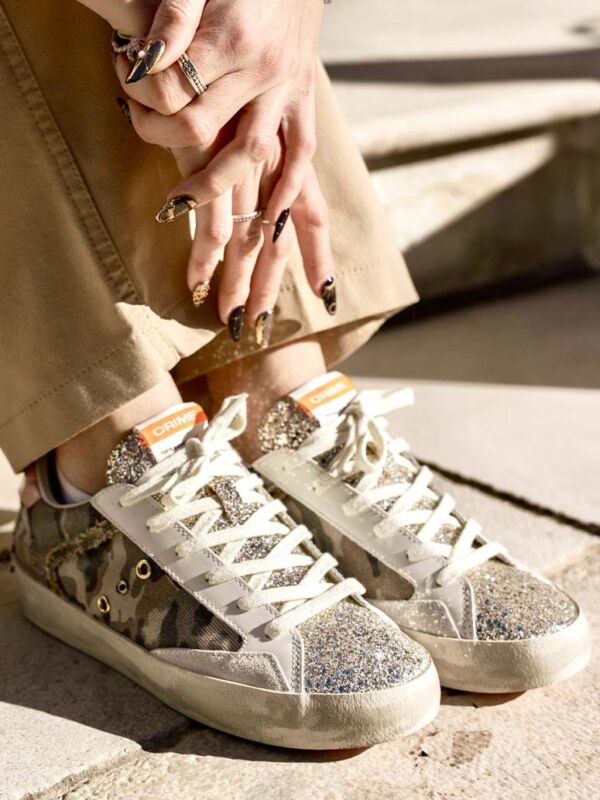 Sneakers femme Crime London à motif militaire kaki avec empiècements pailletés argentés, lacets blancs et semelle effet vintage, portées en extérieur