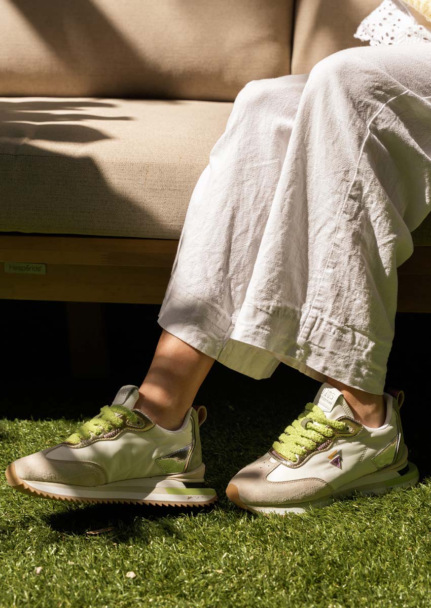 Sneakers 0-105 Lenox Blooming | Dimanche au Jardin & Style Naturel Femme assise sur canapé extérieur portant sneakers 0-105 Lenox Blooming blanches et vertes lacets fourrure pantalon lin blanc jardin ensoleillé détente