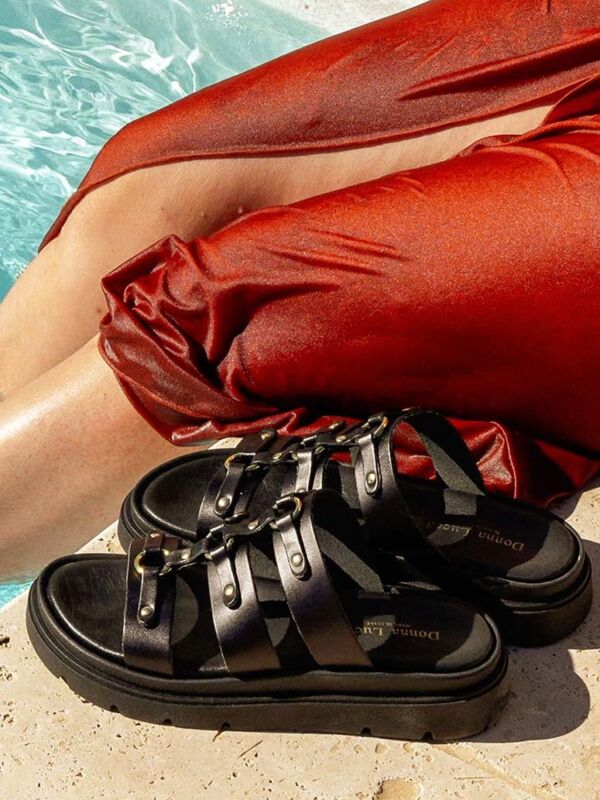 Sandale Donna Lucca 1766 noire à plateforme en cuir avec brides style gladiateur, chaussure femme tendance été 2026 posée au bord d'une piscine