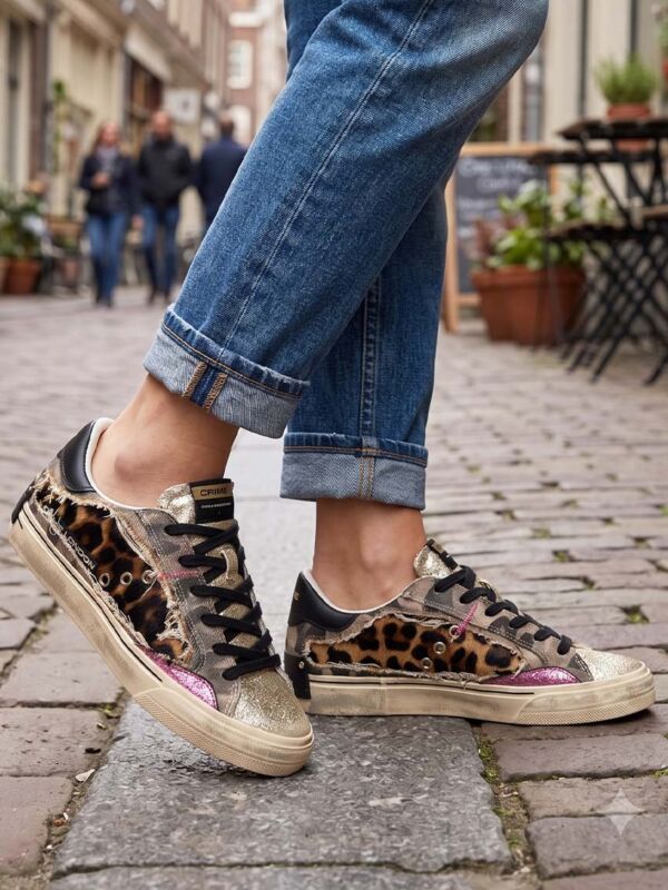 Idée de look street style femme avec la basket Crime London léopard et militaire portée avec un jean denim bleu retroussé. Style urbain et casual chic dans une rue pavée pour inspirer une tenue tendance automne-hiver.