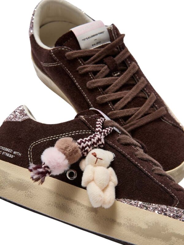 Sneakers femme marron avec ours en peluche et pompons roses accrochés aux lacets - Baskets Crime London avec charms décoratifs amovibles et languette personnalisée tendance 2026-2027