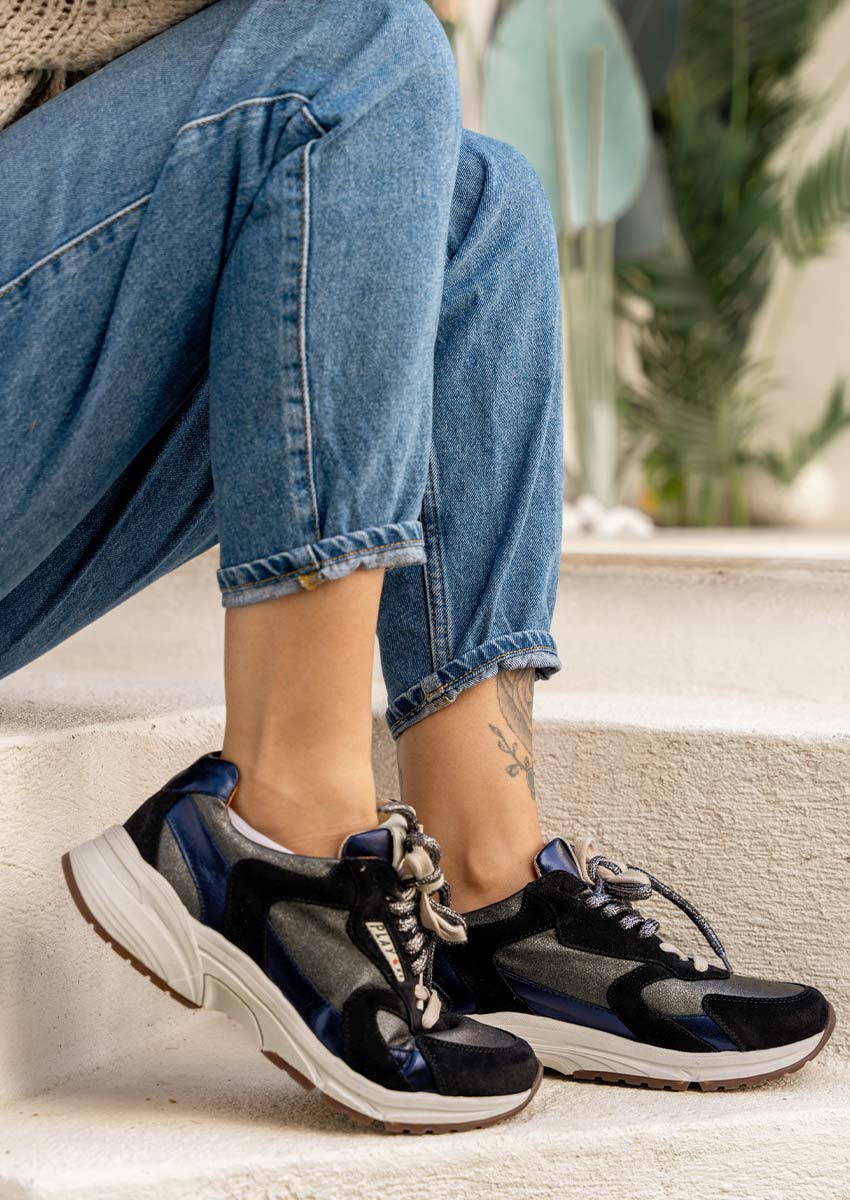 Basket Femme Play One Portée avec Jeans et Pull en Maille – Look Casual Chic Automne-Hiver 2026-2027 Femme assise portant la basket femme Play One noire et bleue métallisée avec jeans bleu denim retroussé et pull en maille beige - Sneaker chunky rétro automne-hiver 2026-2027