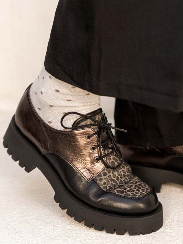 Gros plan du mocassin à lacets JAVA : plateau léopard, cuir bronze métallisé, lacets noirs, chaussettes à pois apparentes