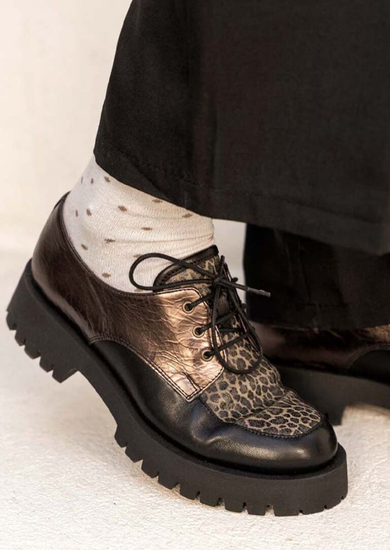 Gros plan du mocassin à lacets JAVA : plateau léopard, cuir bronze métallisé, lacets noirs, chaussettes à pois apparentes