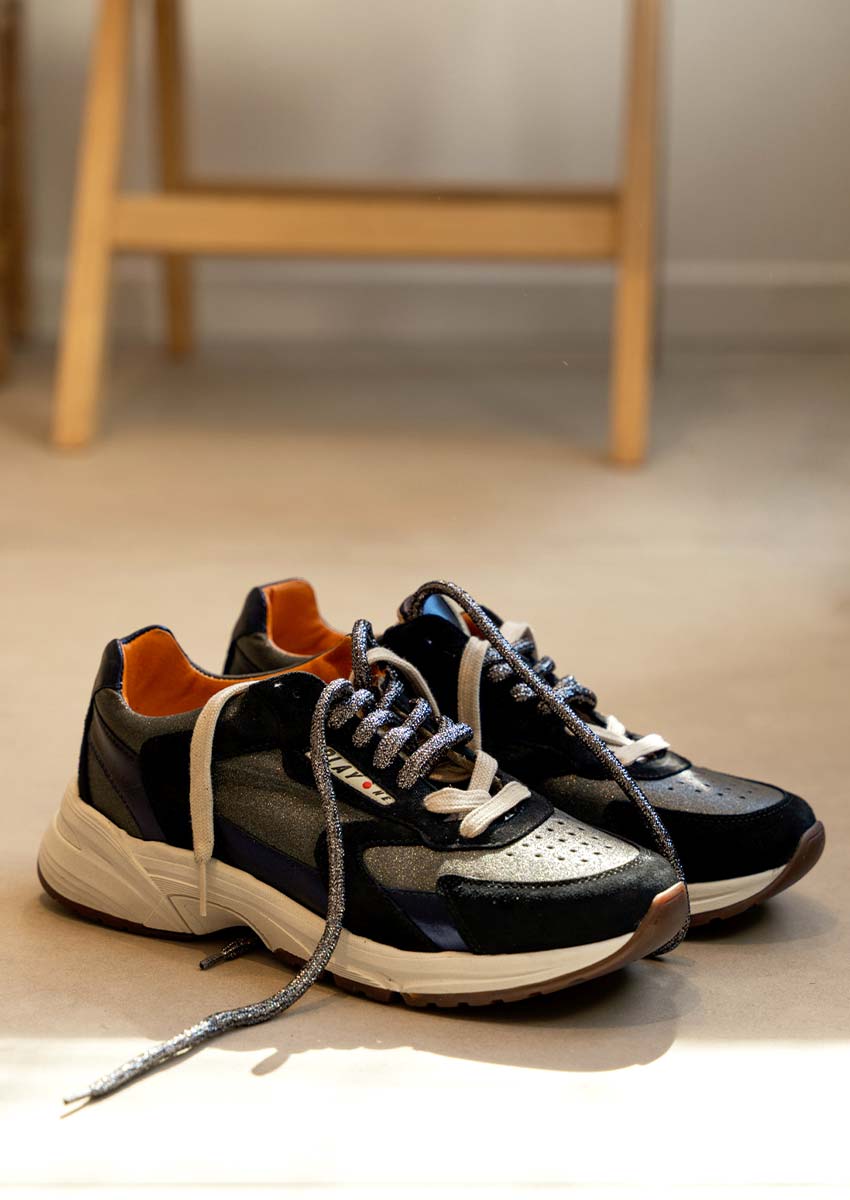 Paire de Baskets Femme Play One Noires et Bleues Métallisées – Sneakers Chunky Rétro AH 2026-2027 Paire de baskets femme Play One noires et bleues métallisées posées au sol - Sneakers chunky rétro à lacets doubles, doublure orange et semelle épaisse blanche automne-hiver 2026-2027